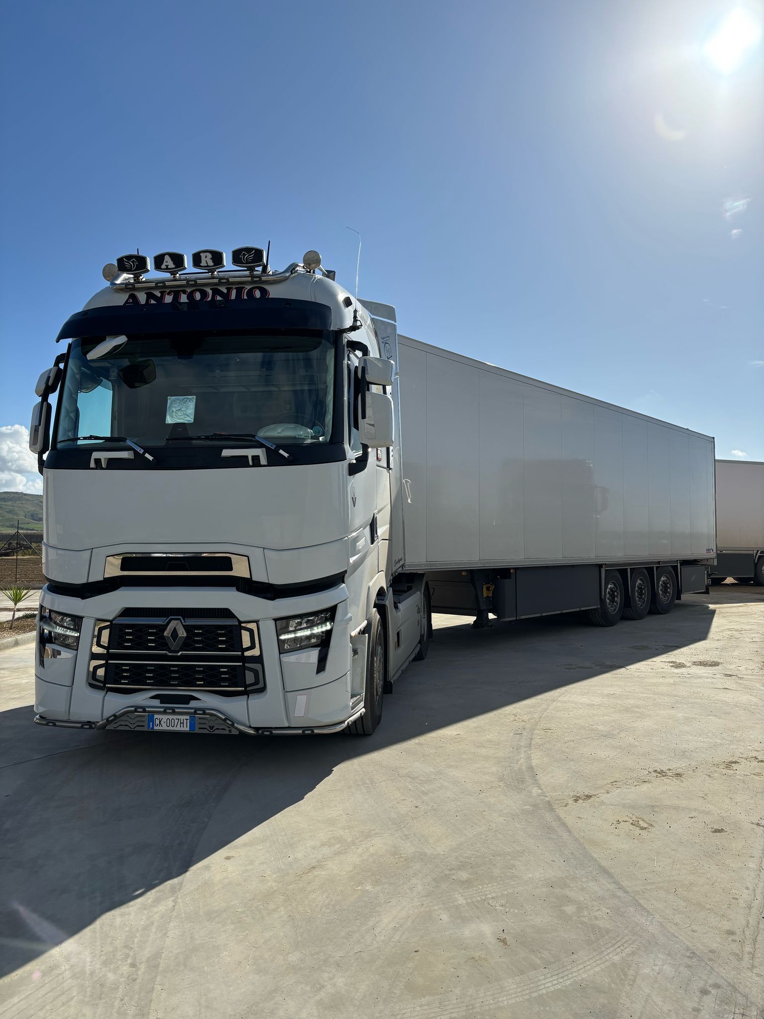 Un camion bianco con rimorchio è parcheggiato in un parcheggio.