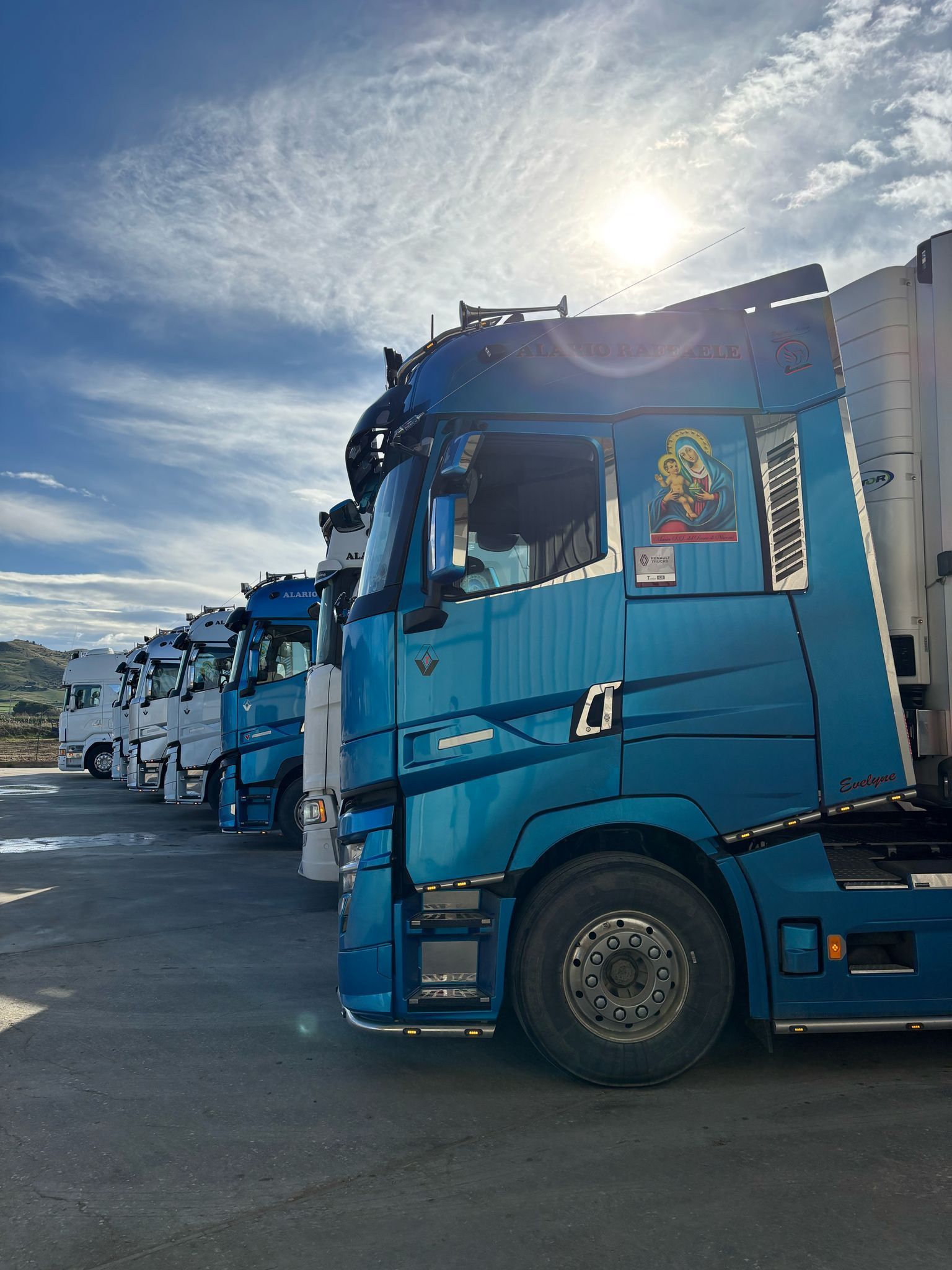 Una fila di camion blu sono parcheggiati in un parcheggio.