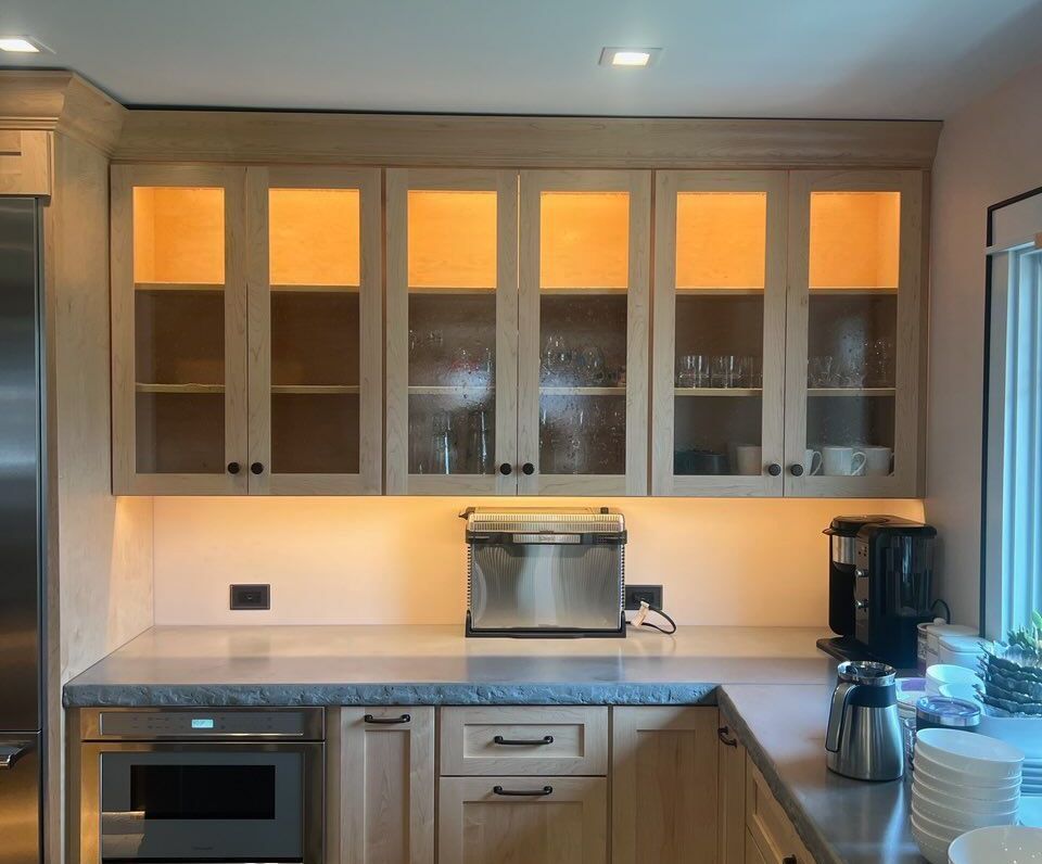 Kitchen cabinets with lit glass doors, countertop with appliances (toaster, coffee maker), and microwave.