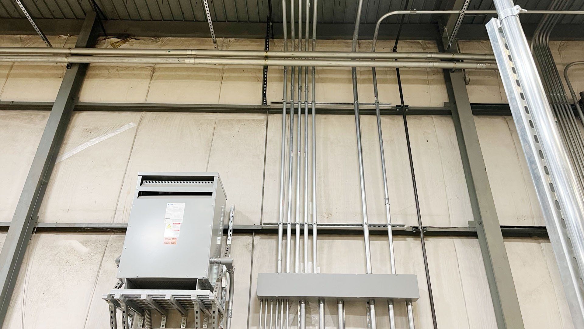 There are a lot of wires hanging from the ceiling of a building.