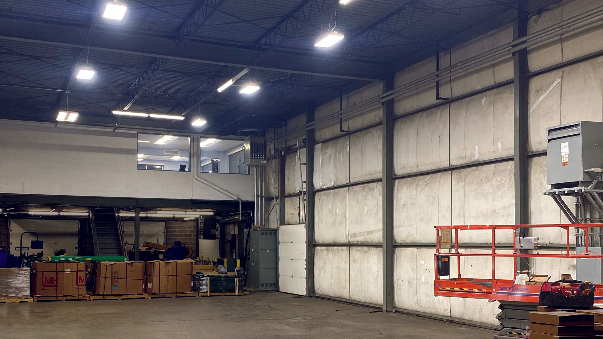 A large warehouse with a lift in the middle of it and new lighting.
