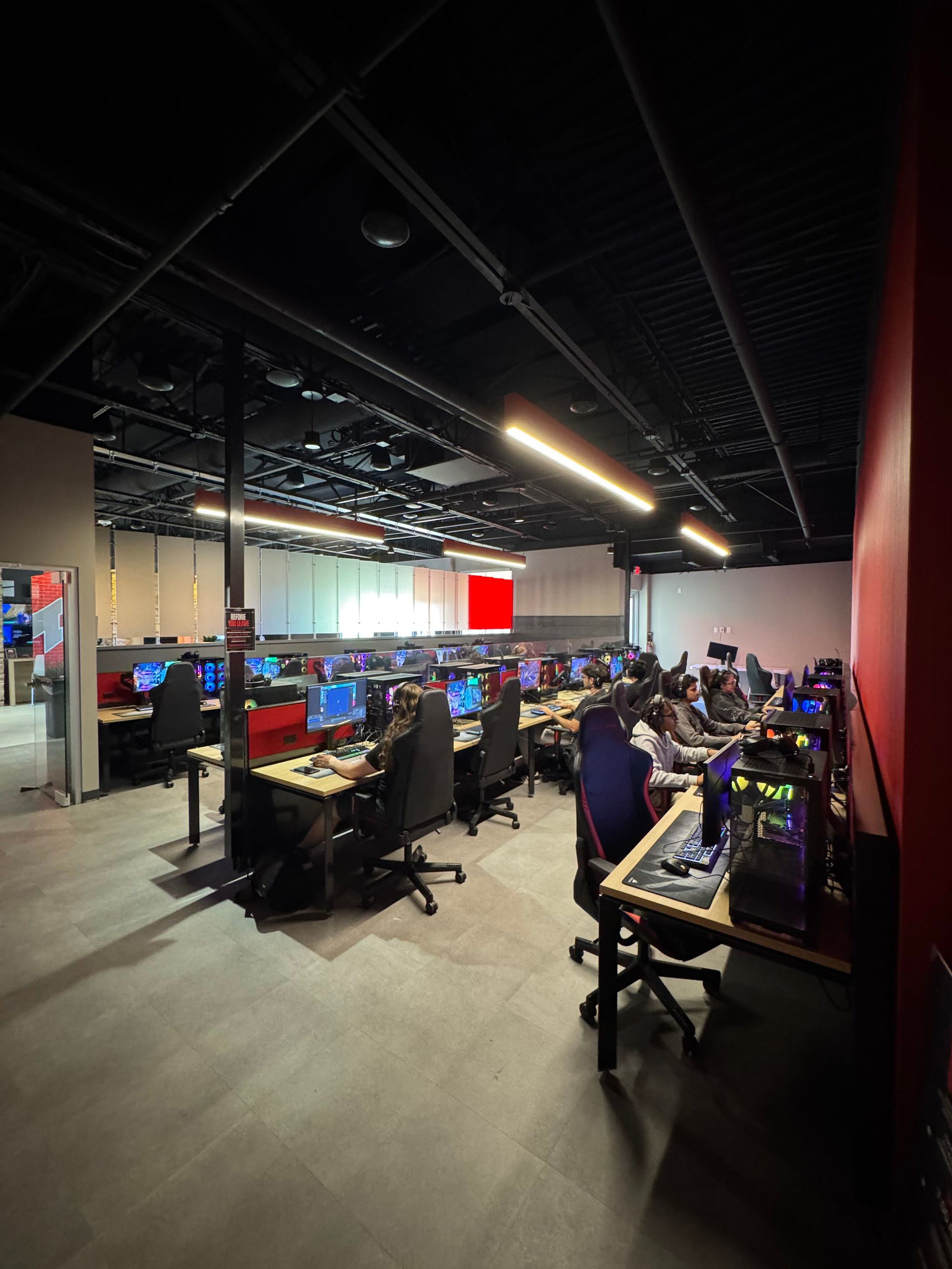 Open office with rows of computers and people working under bright ceiling lights