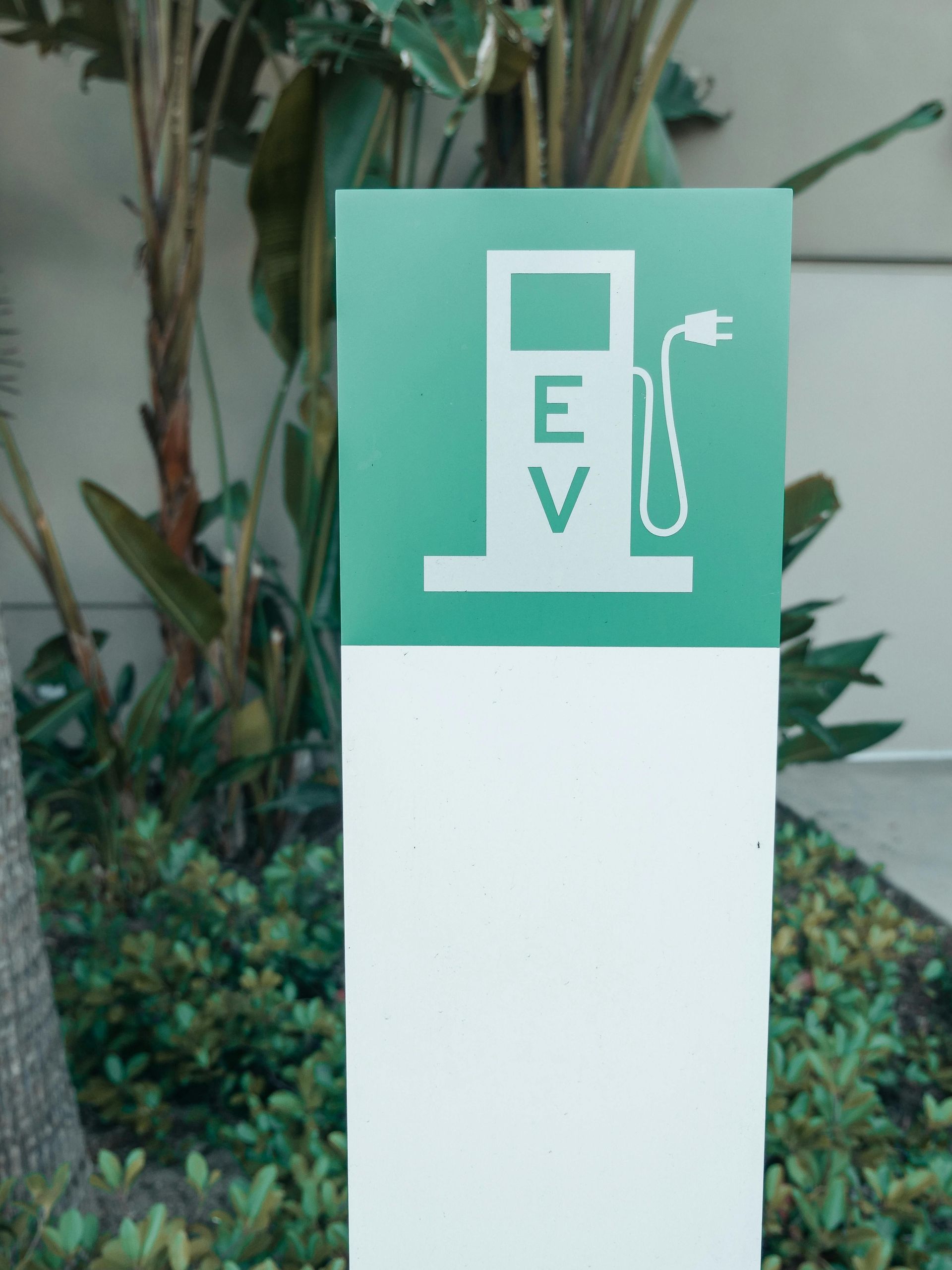 EV charging station sign with green top and white base outdoors