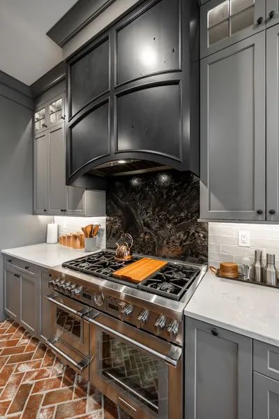 A kitchen with stainless steel appliances and gray cabinets.