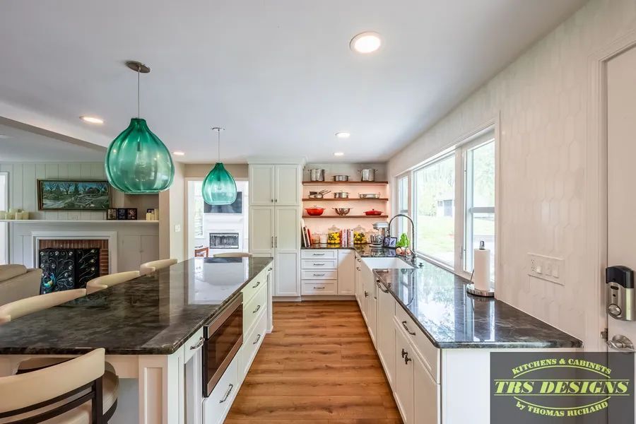 A kitchen with white cabinets and black granite counter tops.