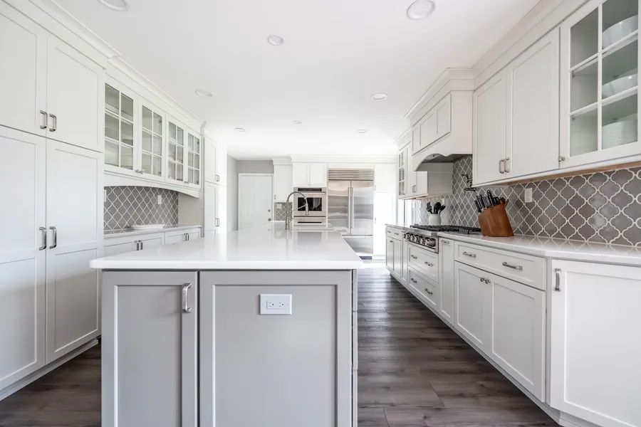 A kitchen with white cabinets and a large island in the middle.