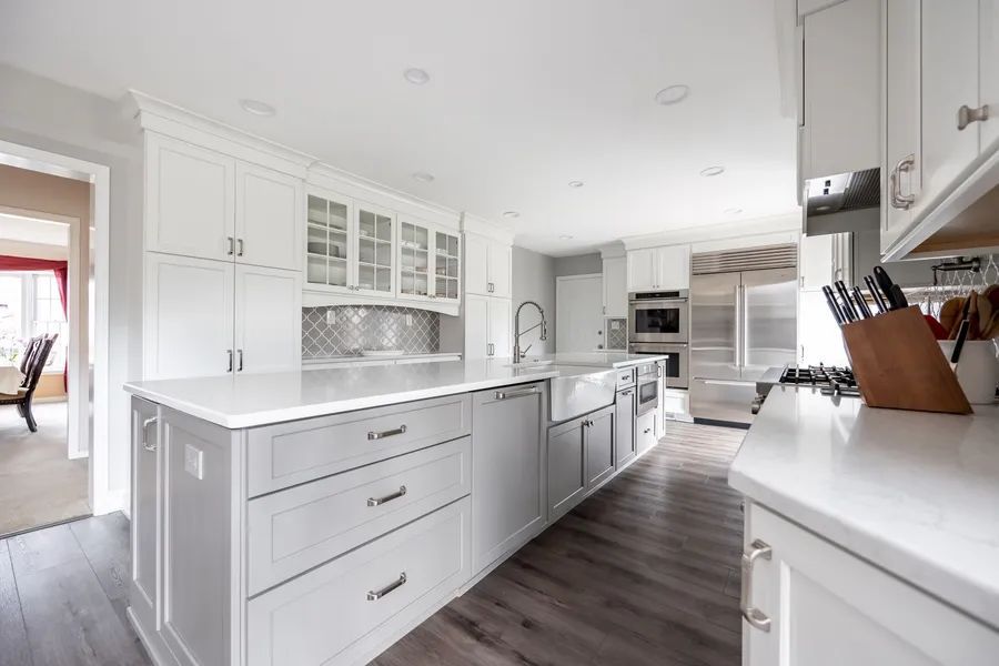 A kitchen with white cabinets and a large island in the middle.