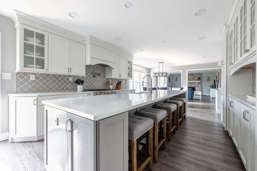 A kitchen with white cabinets and a large island with stools.