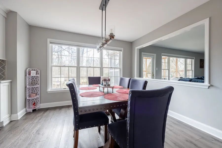 A dining room with a table and chairs and a large mirror.