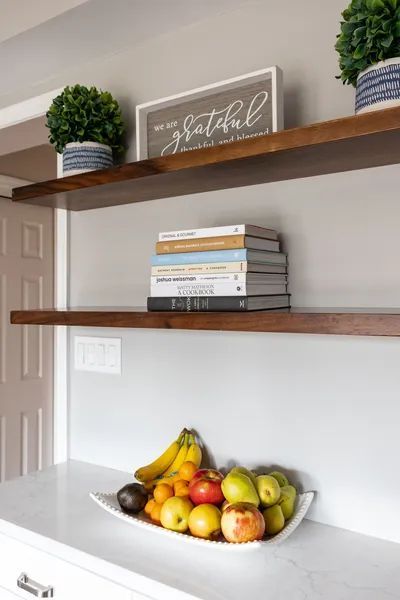 A bowl of fruit sits on a counter next to a sign that says 