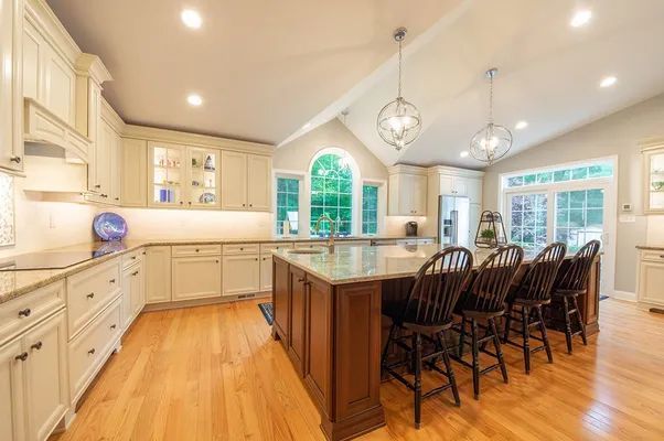 A kitchen with white cabinets , granite counter tops , and a large island.