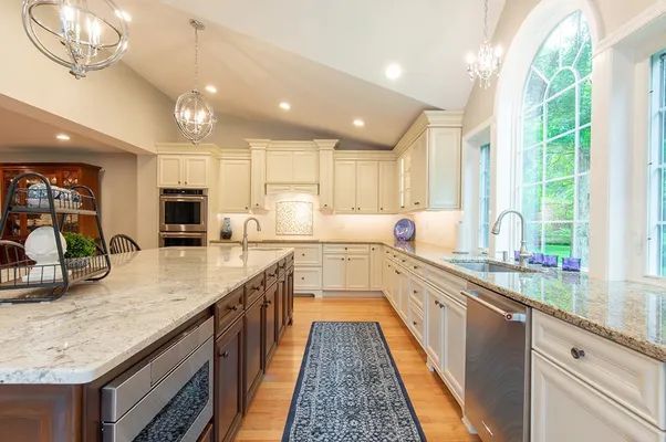 A kitchen with white cabinets , granite counter tops , and stainless steel appliances.