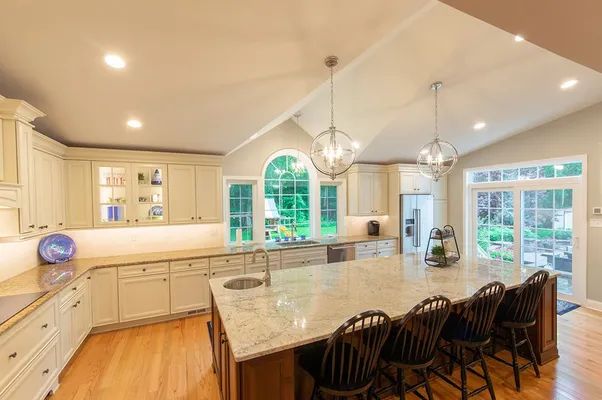 A kitchen with white cabinets , granite counter tops , and a large island.