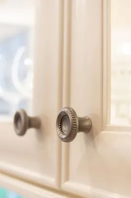 A close up of a cabinet with a glass door and a metal handle.