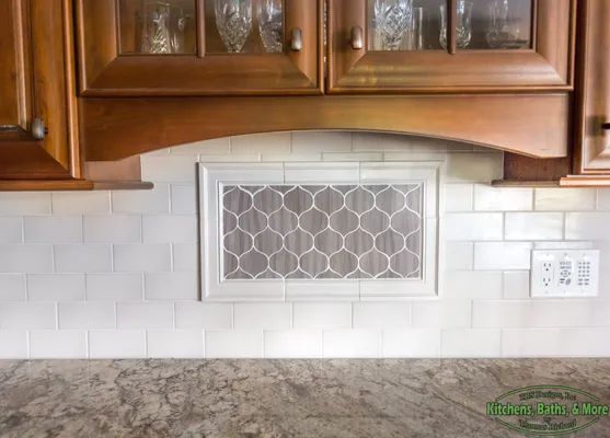 A kitchen with wooden cabinets and white tiles on the wall.