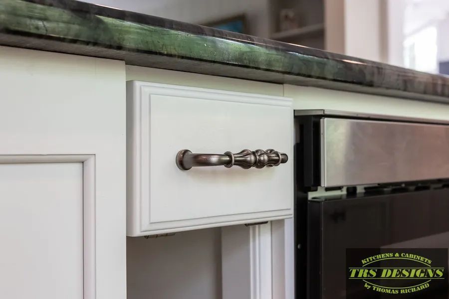 A kitchen with white cabinets and a stainless steel refrigerator.