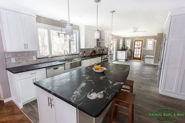 A kitchen with white cabinets and black granite counter tops.