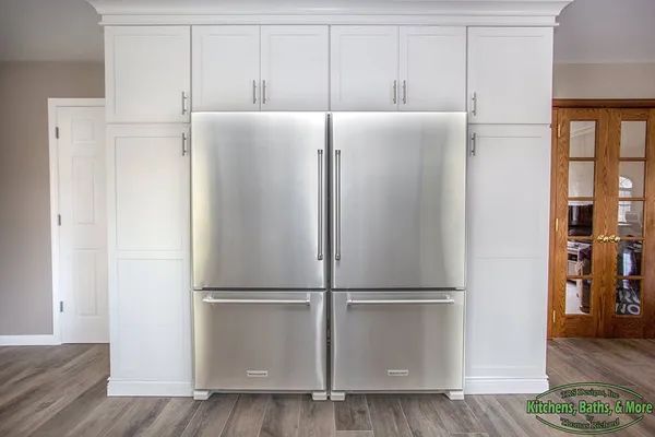A stainless steel refrigerator and freezer are built into a wall in a kitchen.