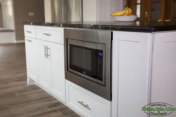 A kitchen with a microwave and a bowl of bananas on the counter.