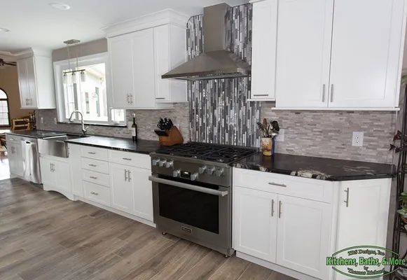 A kitchen with white cabinets, black counter tops, and a stove.