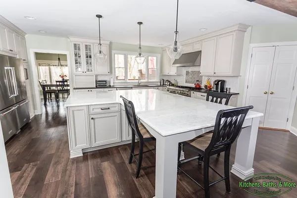 A kitchen with white cabinets and a large island with a table and chairs.