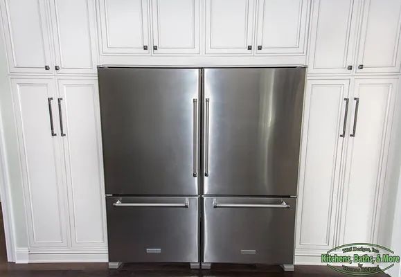 A stainless steel refrigerator in a kitchen with white cabinets.