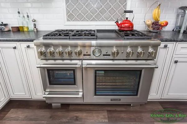 A stainless steel stove and oven in a kitchen with white cabinets.