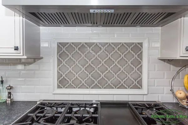 A kitchen with a stove top oven and a stainless steel hood.
