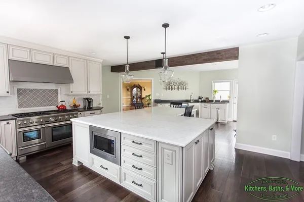A kitchen with white cabinets, stainless steel appliances, and a large island.