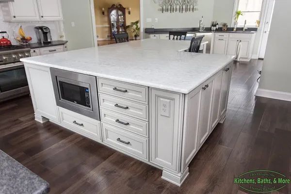 There is a large island in the middle of the kitchen with a microwave.