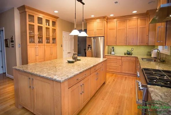 A kitchen with wooden cabinets, granite counter tops, stainless steel appliances and a large island.