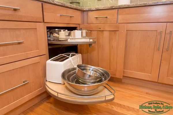 A kitchen with wooden cabinets, a toaster oven, bowls, and a sliding shelf.