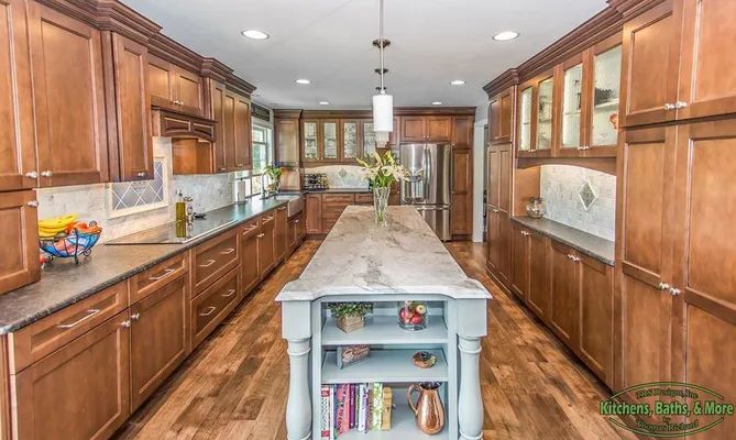 A long kitchen with wooden cabinets and a large island in the middle.