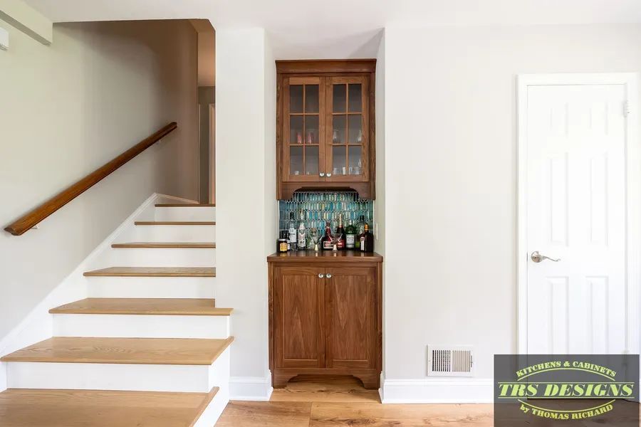 There is a bar in the corner of the room next to the stairs.