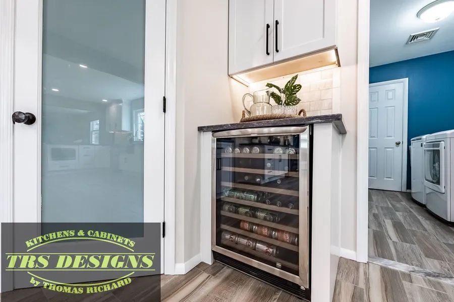 A wine cooler is sitting on top of a counter in a kitchen.