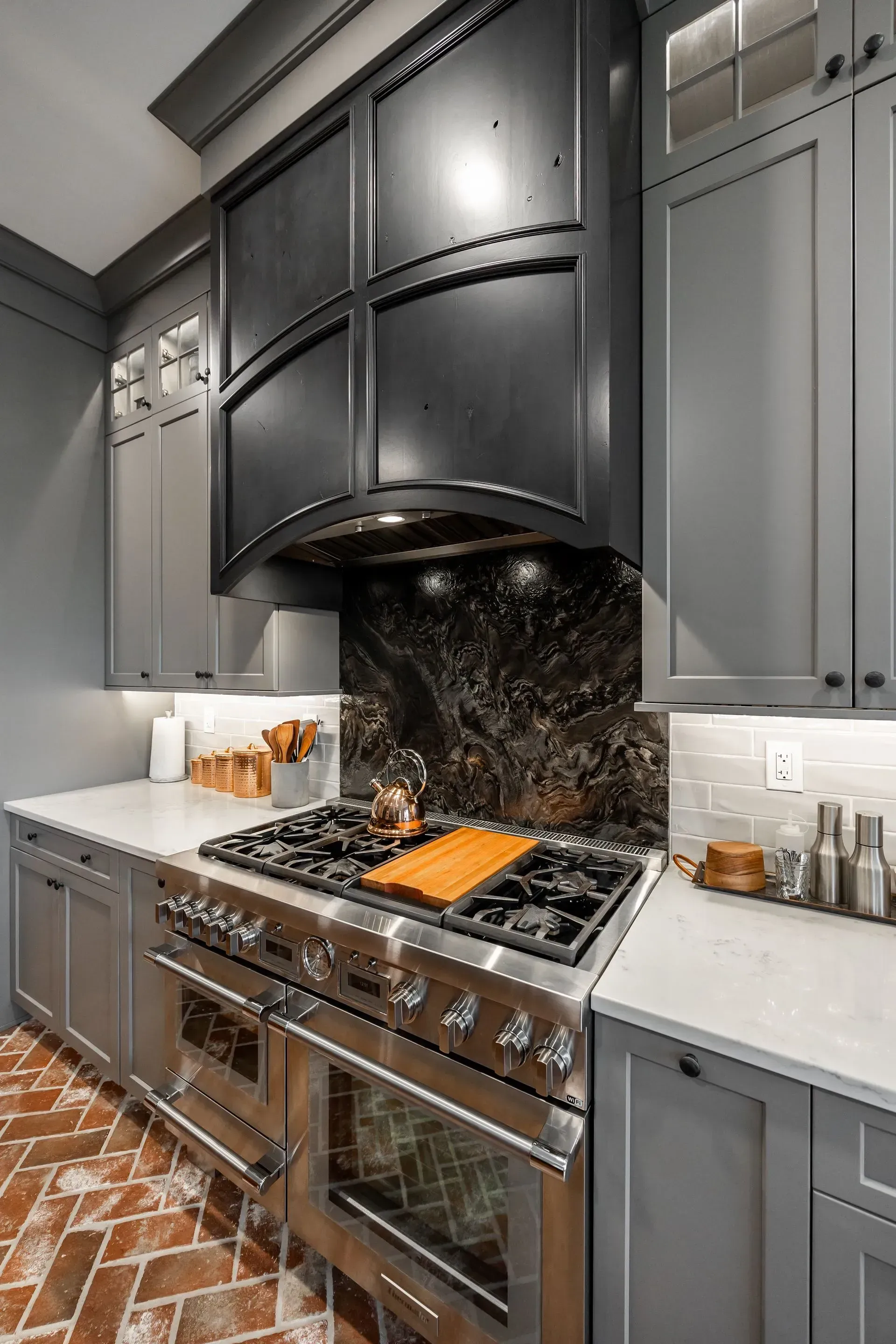 A kitchen with stainless steel appliances and gray cabinets.