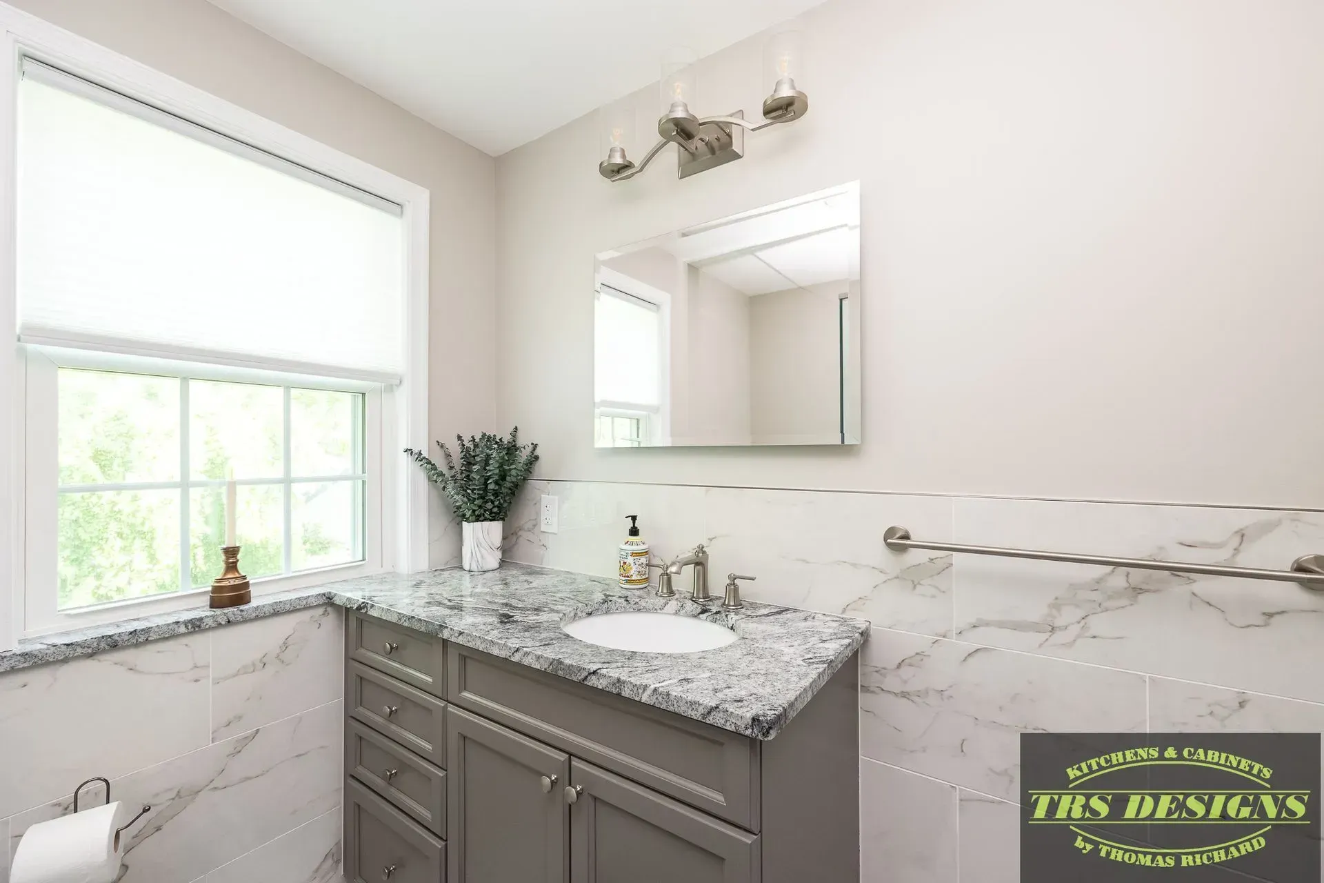 A bathroom with a sink, mirror and window.