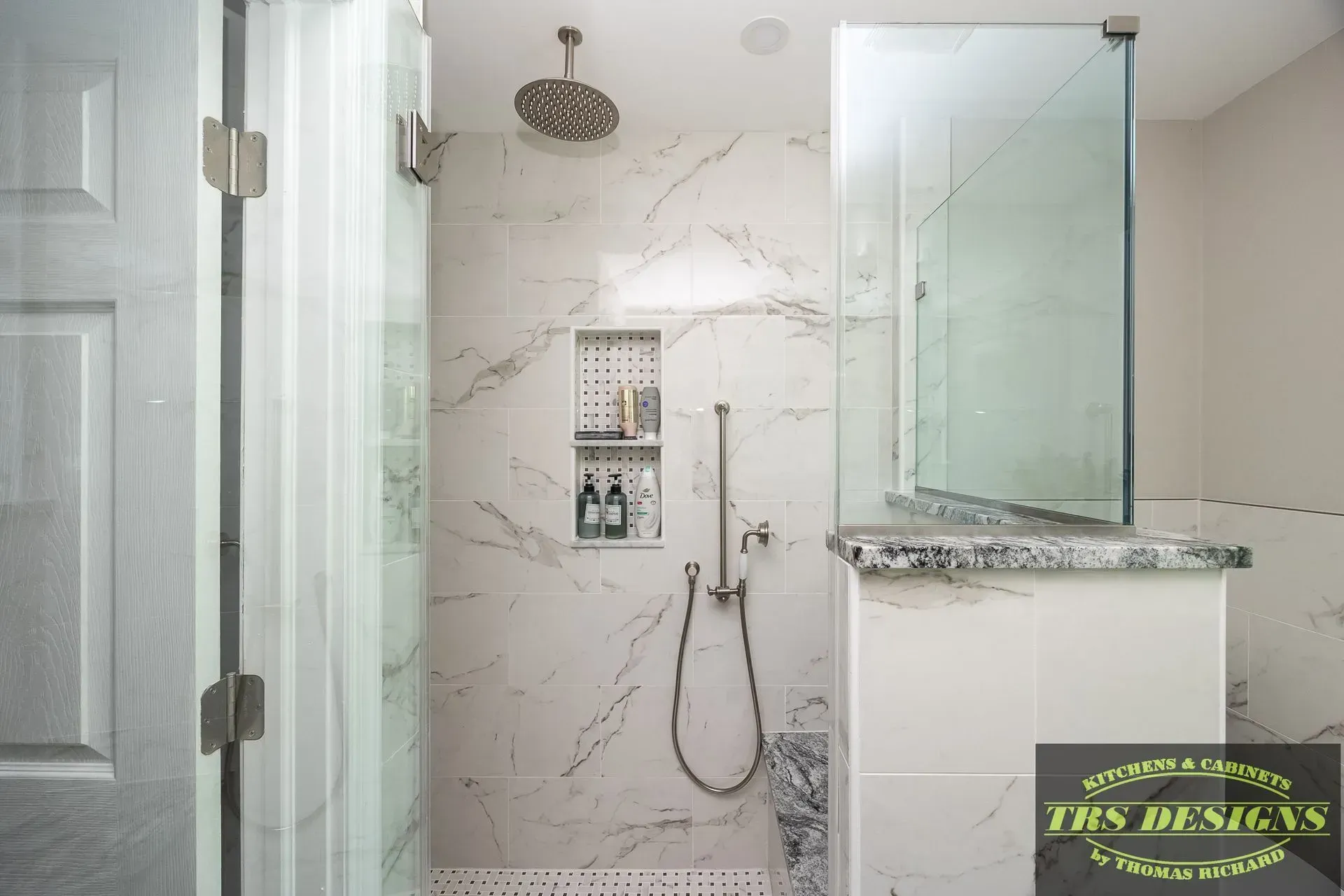 A bathroom with a walk in shower with a glass door.