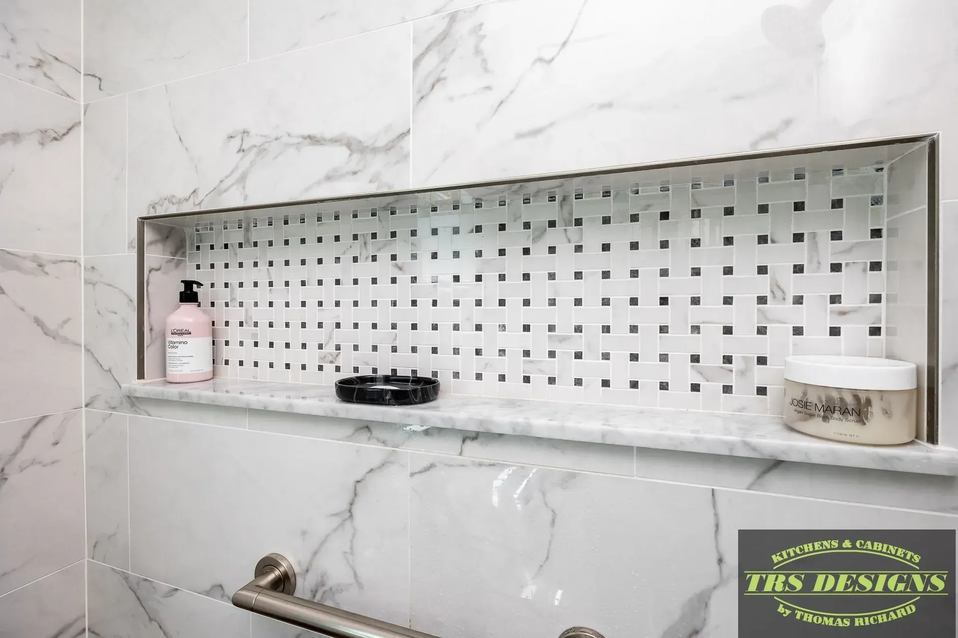 A bathroom with a marble wall and a shelf with a bottle of lotion on it.