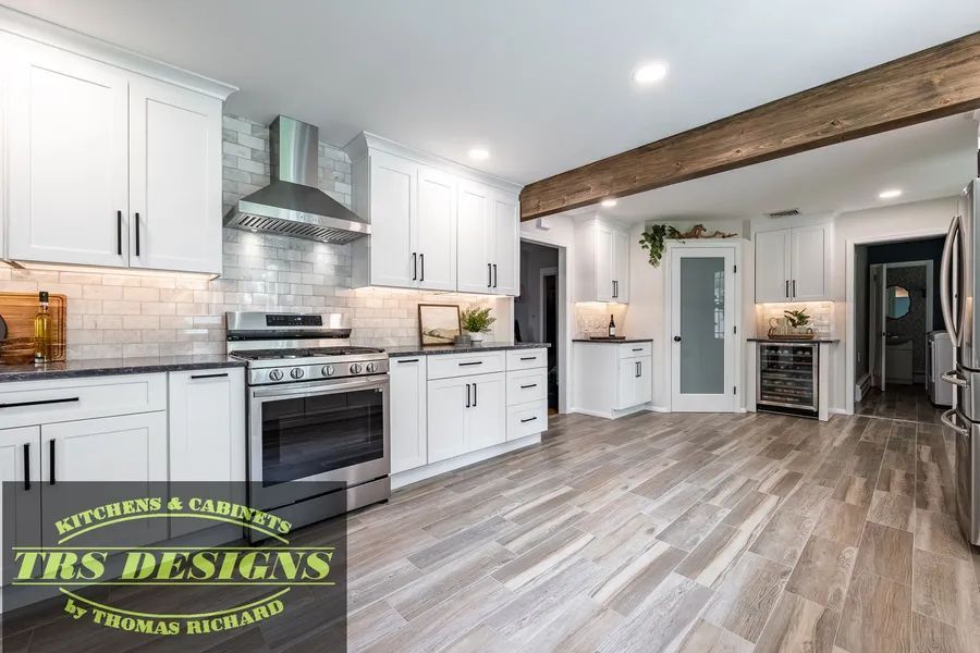 A kitchen with white cabinets, stainless steel appliances, and wooden floors.