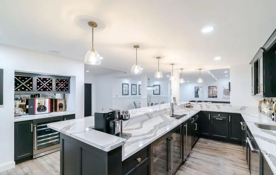A large kitchen with black cabinets and white counter tops.