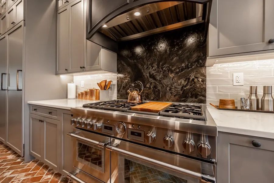 A kitchen with stainless steel appliances and gray cabinets.