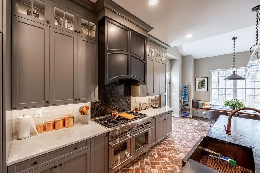 A kitchen with gray cabinets , stainless steel appliances, a sink and a stove.