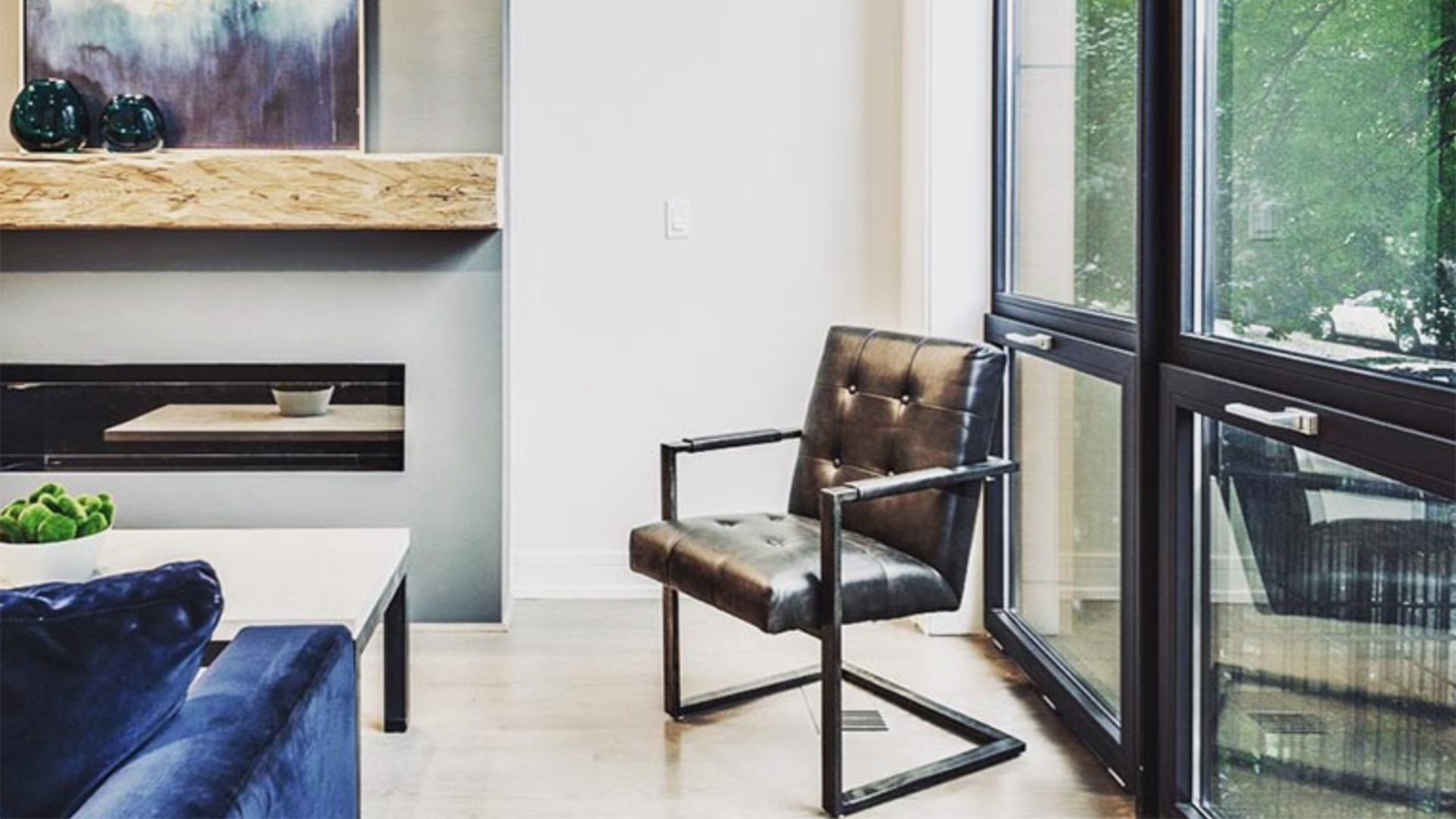 A living room with a chair , couch , fireplace and large windows.
