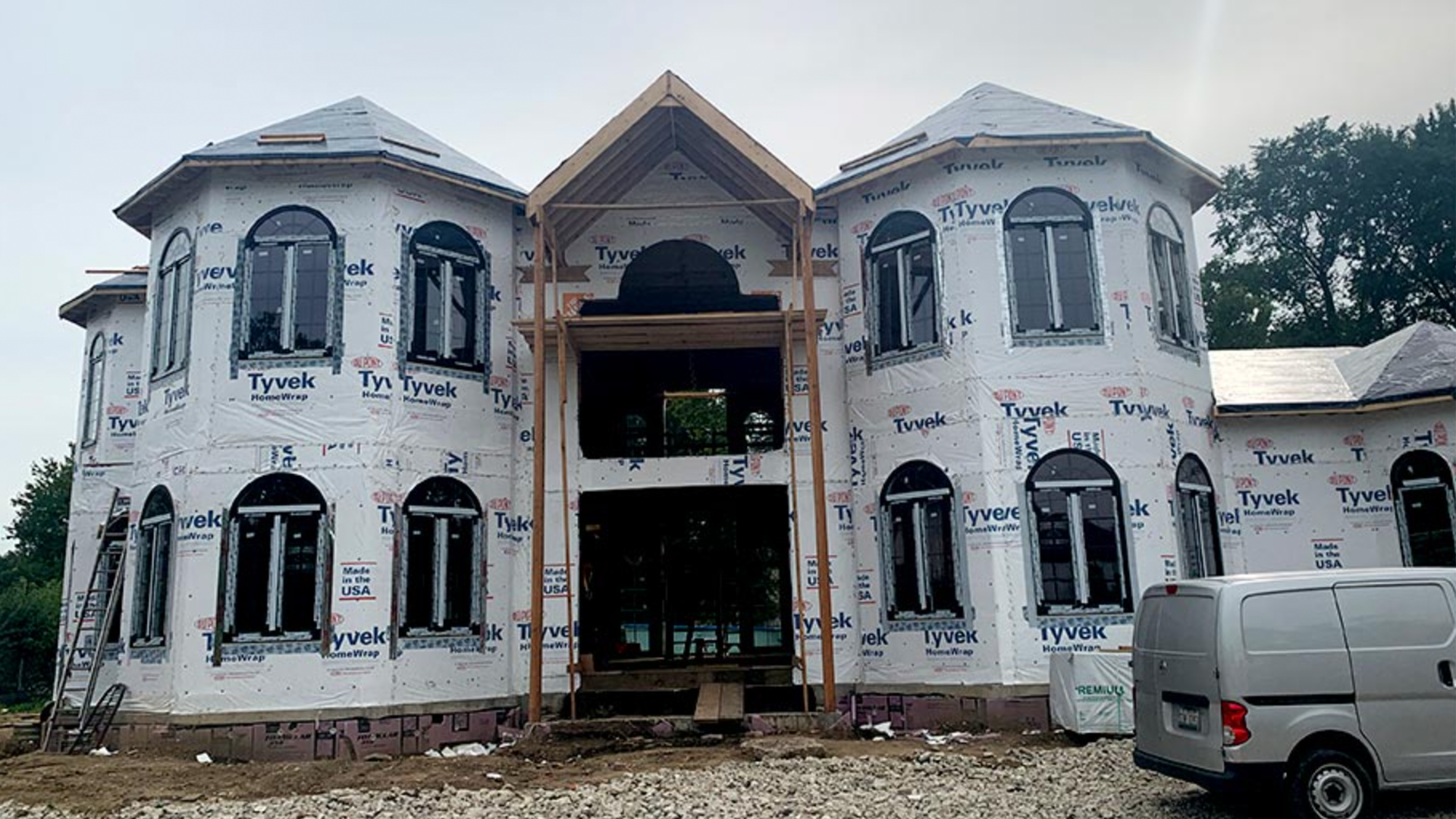 A large house under construction with a van parked in front of it.