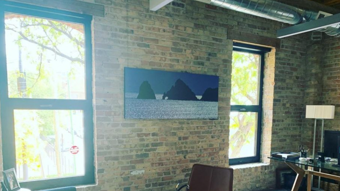 A living room with a brick wall and a painting on the wall.