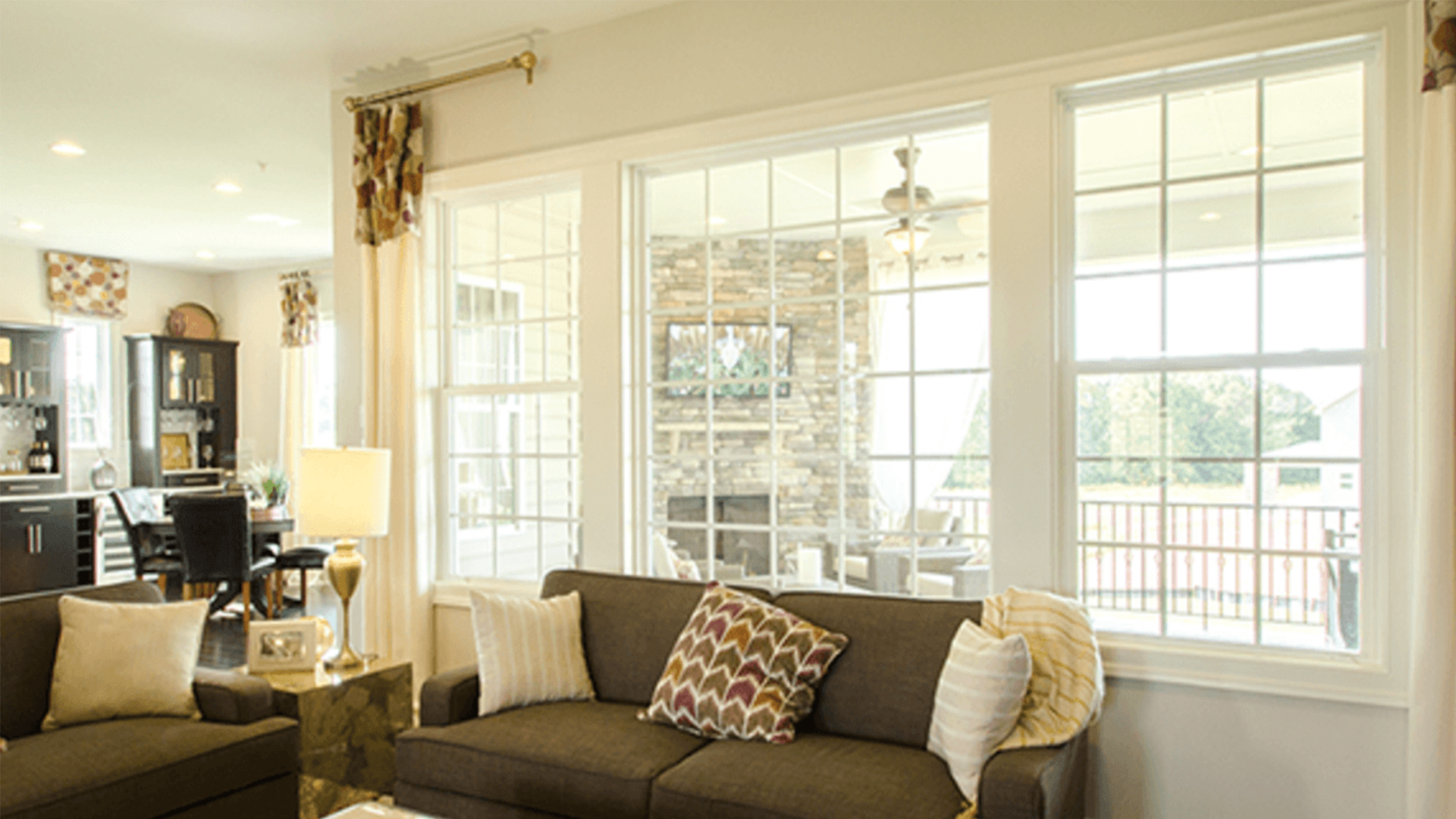 A living room with a couch , two couches , a table , and a lot of windows.