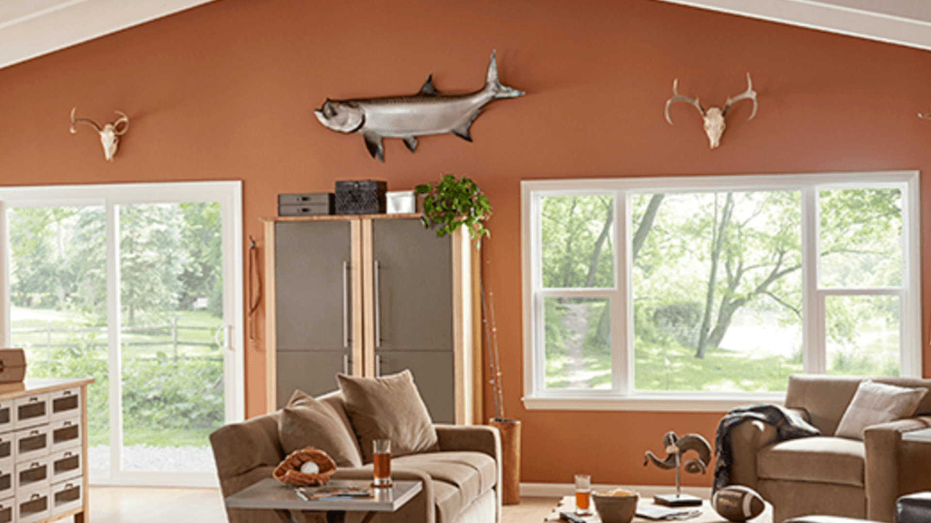 A living room with a couch , chairs , and a fish on the wall.