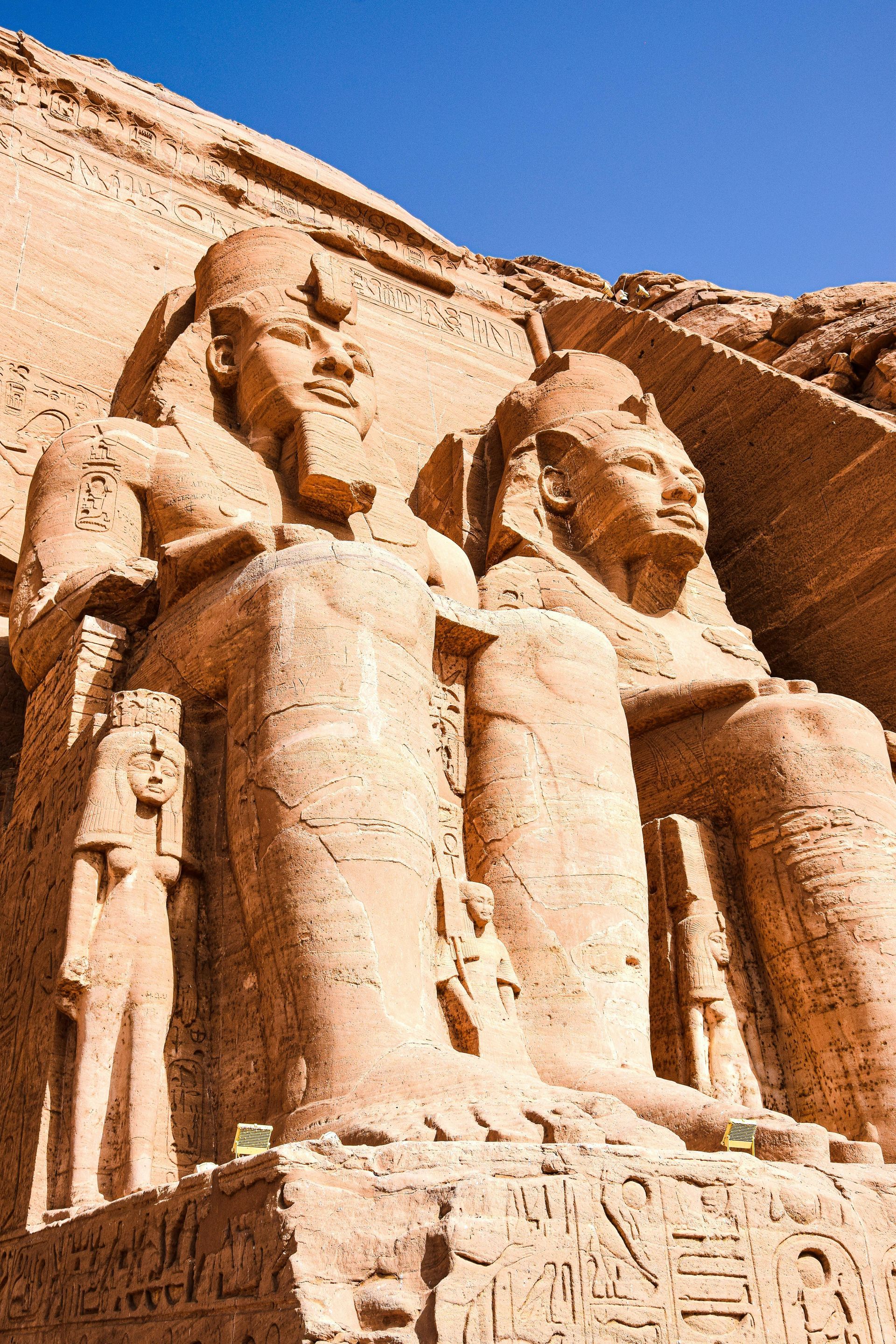 Two seated colossal statues of pharaohs at Abu Simbel, Egypt. Sunlight on sandstone.
