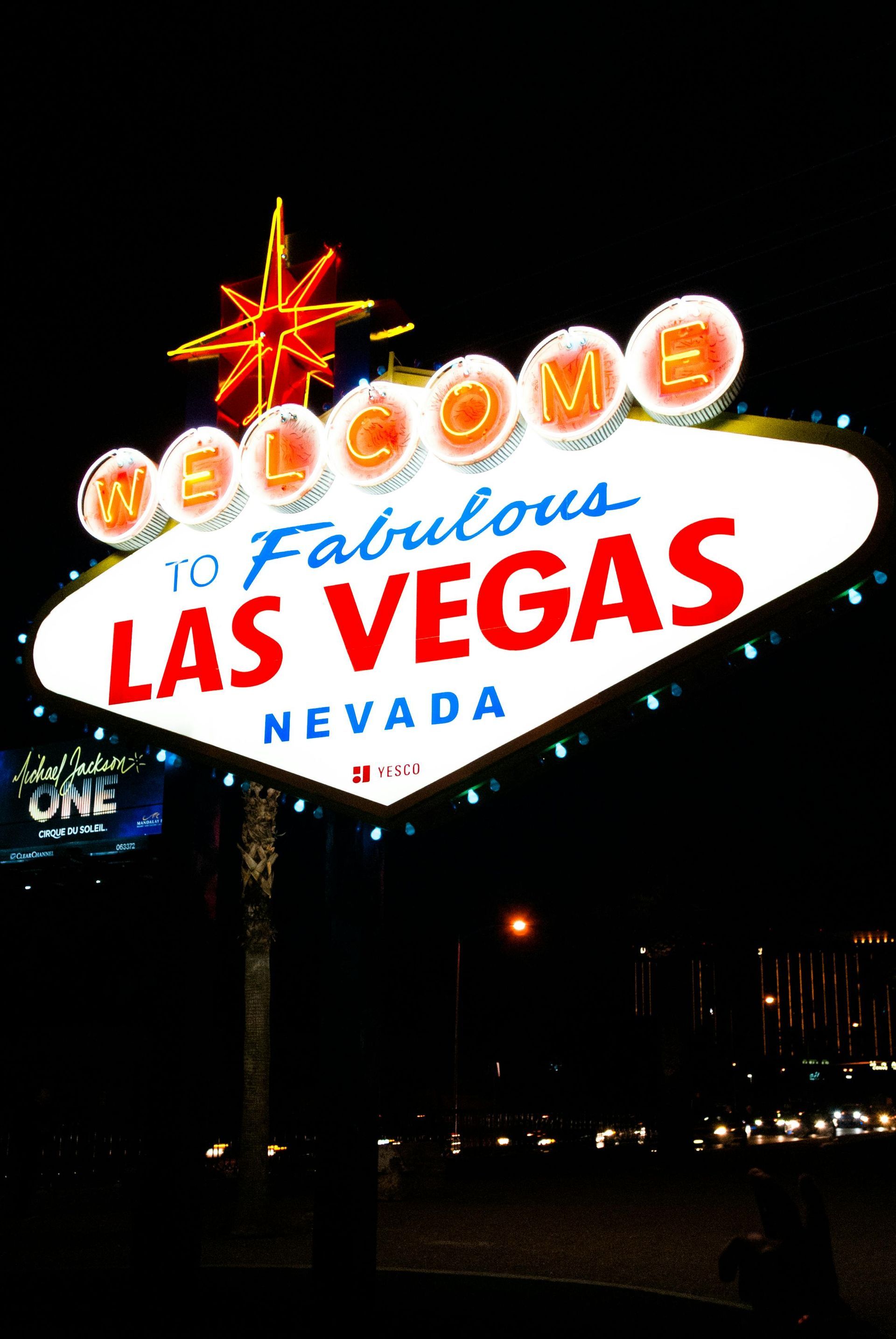 Welcome to Fabulous Las Vegas sign at night, lit with bright lights. Starburst on top, dark background.